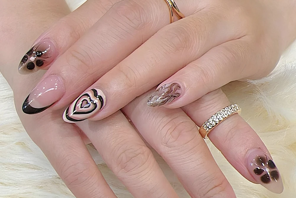 Almond nails with hand-painted hearts, black French tips and smoky flowers